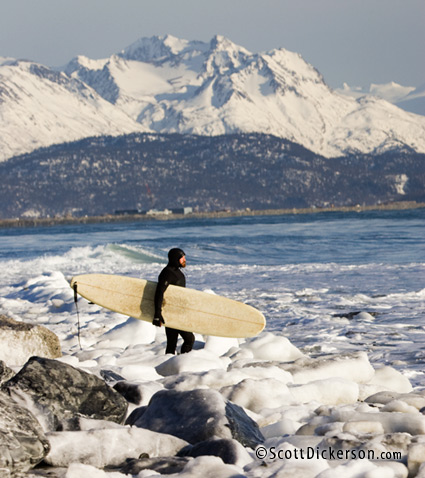 Alaskan surfer Ty Gates walks through chunks of ice on the beach.