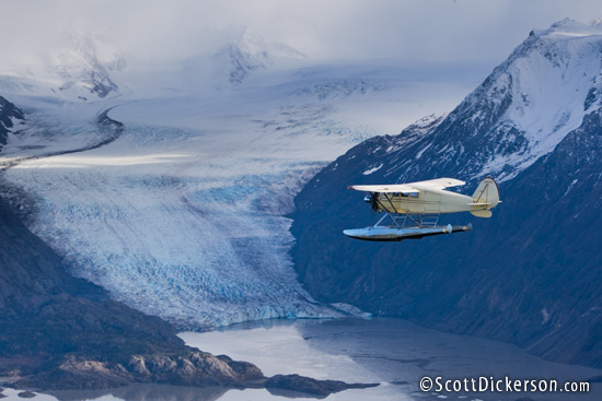 Air to air aerial photo of 1933 Stinson JR. SR floatplane flying by Grewingk Glacier and the Kenai Mountains, Alaska.