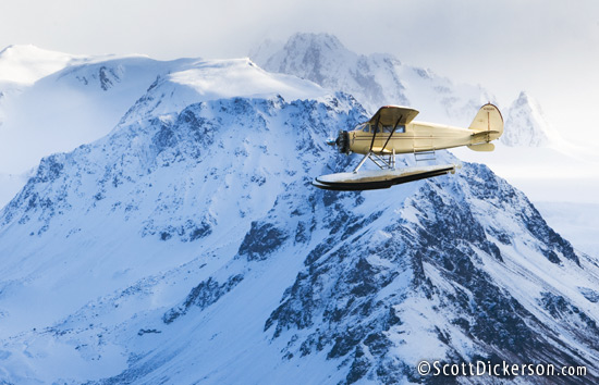 Air to air aerial photo of 1933 Stinson Jr. Sr floatplane flying through Kenai Mountains, Alaska.