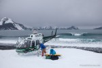 Helisurfing in Alaska in winter. Helicopter, surfboards, mountains, and waves.