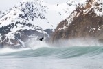 Ian Walsh surfing in Alaska beneath snow covered mountains.