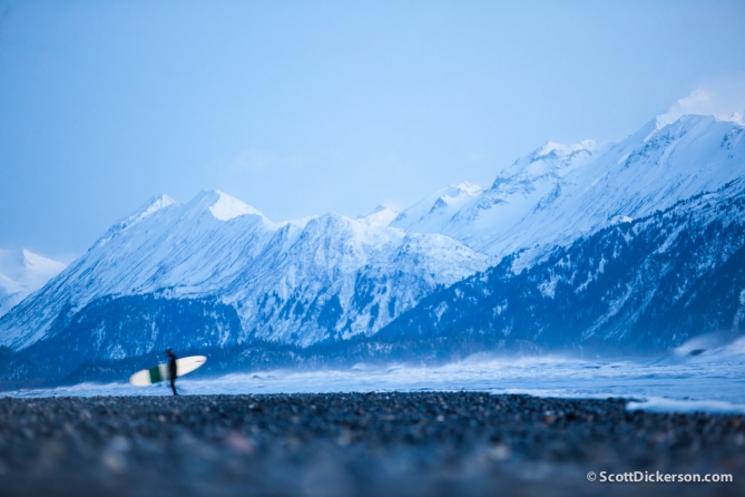 surfing in Alaska with snow covered mountains